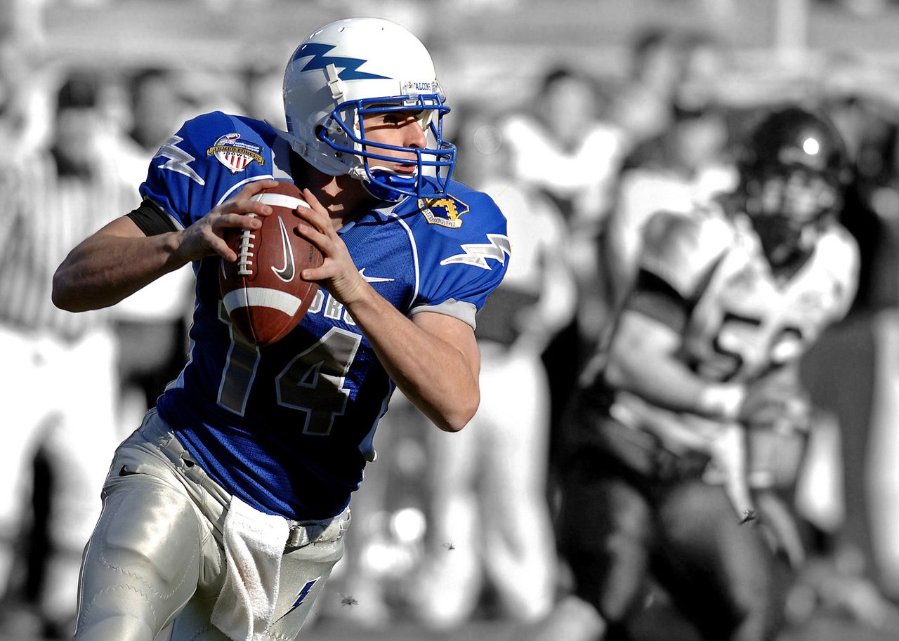 Football player in blue uniform preparing to throw a ball on a field.